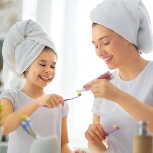 a mother and daughter brush their teeth together