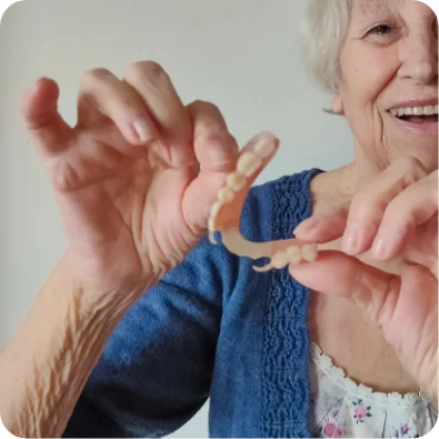 An elderly patient holding prosthetic partial dentures